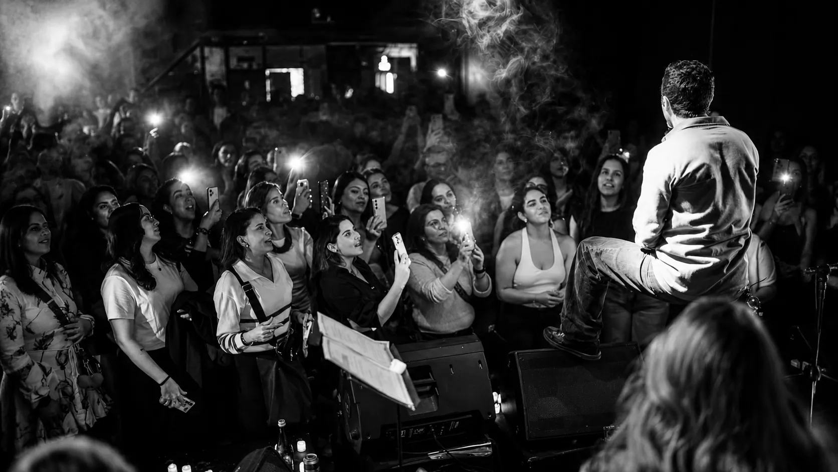 Público en blanco y negro con las caras iluminadas por las linternas de sus teléfonos