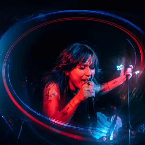 Vocalista cantando envuelta en una estela de luz roja y azul